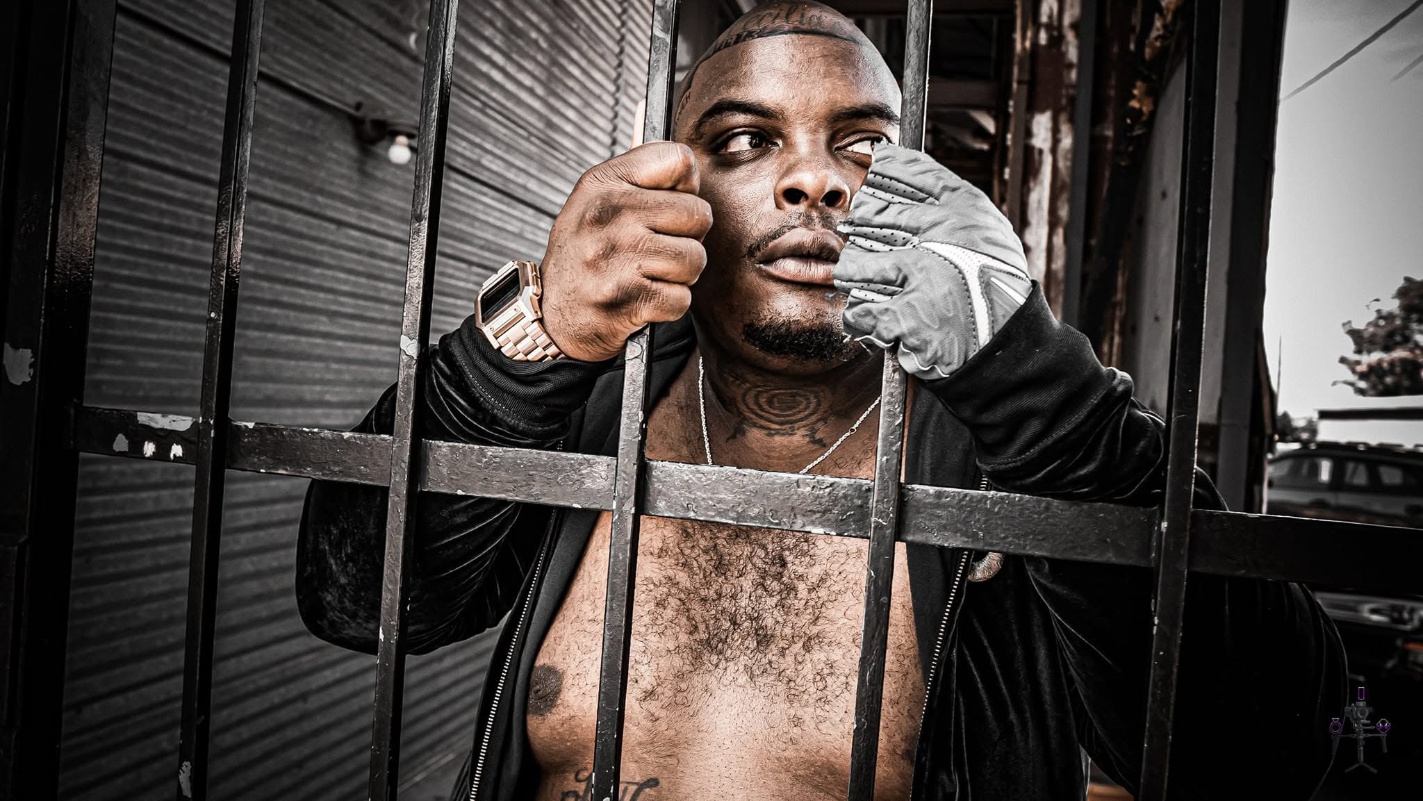 Editorial portrait photographed through a metal fence by J Sturgis Media