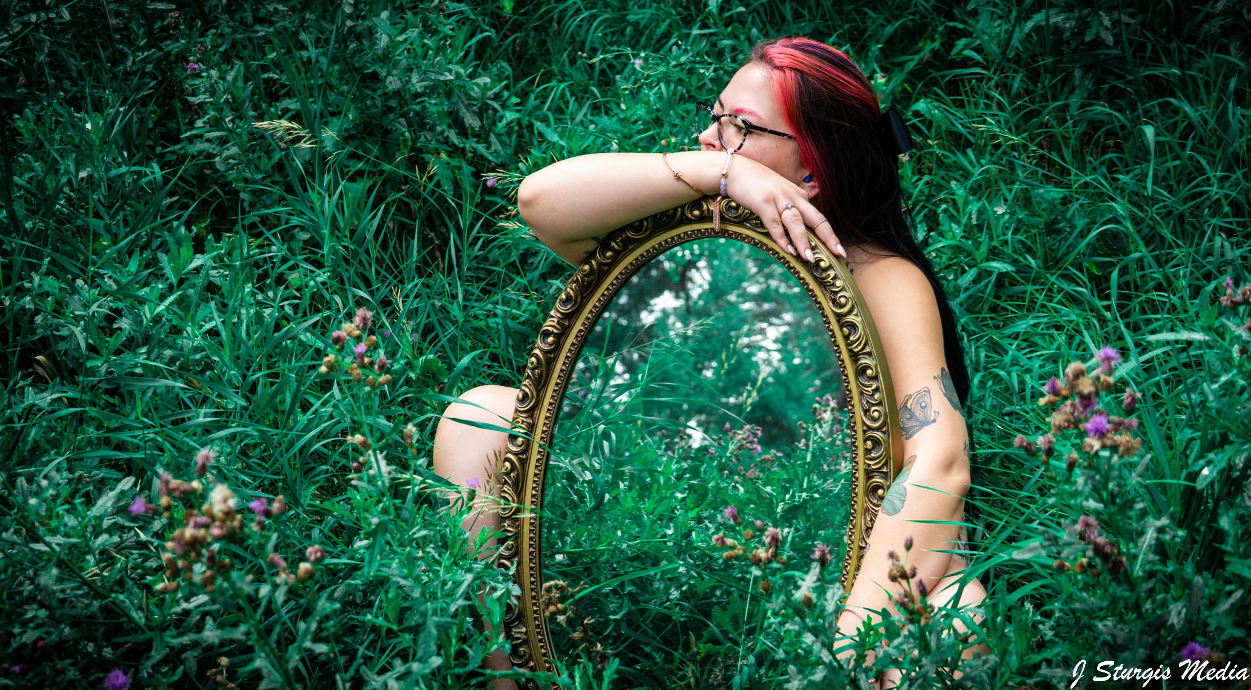 Creative senior portrait with a mirror in a green outdoor setting by J Sturgis Media